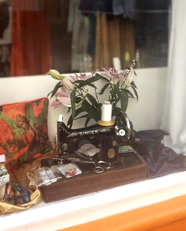 A vintage Singer sewing machine with lilies and a cushion
